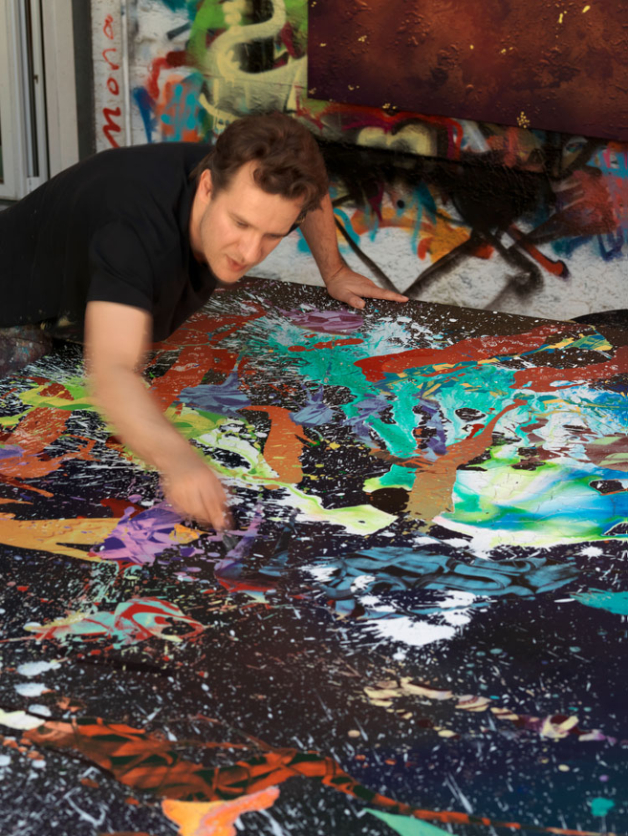 It shows the artist in his studio while he is making one of his paintings.