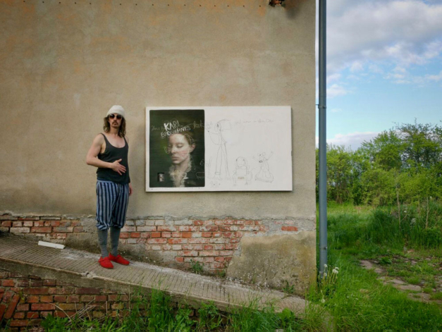 The artist Mike is shown with one of his artworks at a street exhibition.