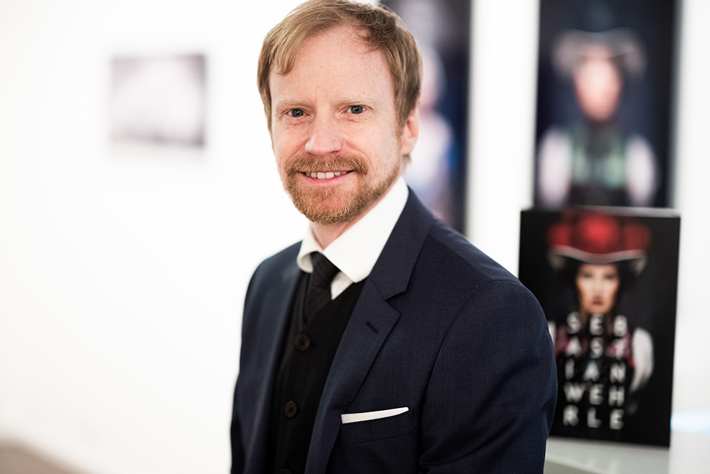 CEO at an art exhibition showing a catalog.